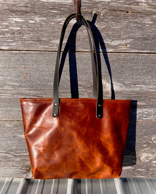 Chestnut brown leather Wanderer tote bag with black leather straps and copper hardware.
Simple. Rugged. Dependable.