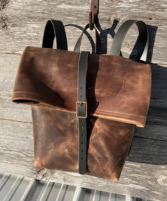 Frontier Rucksack roll top backpack in cowboy brown leather, black leather straps and copper hardware.