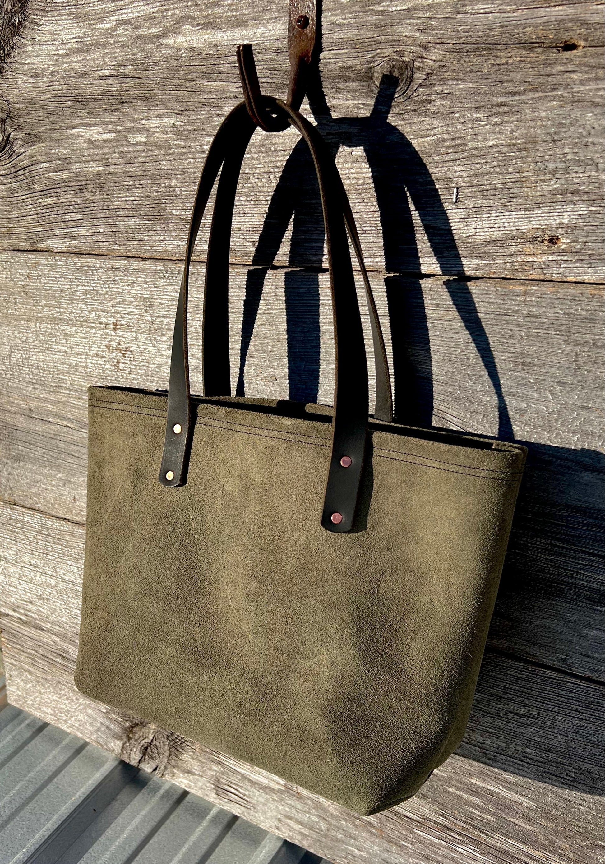 Medium green suede leather Wanderer tote bag with black leather straps and copper hardware.