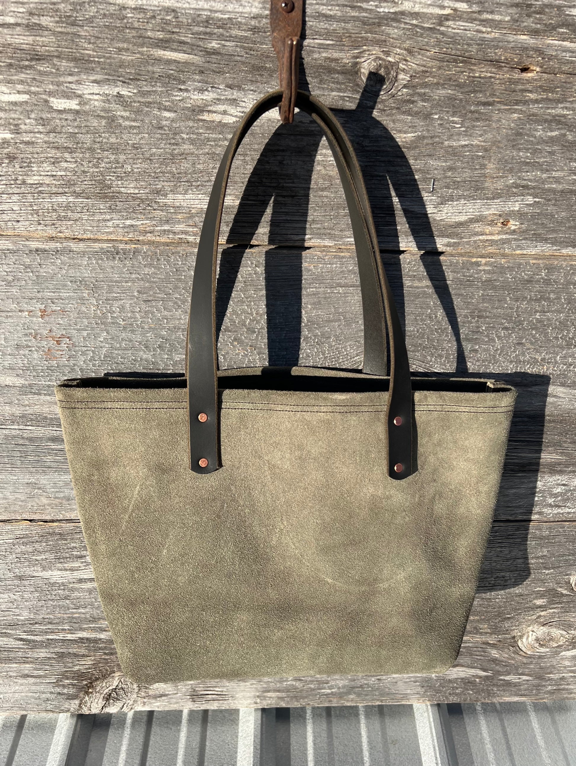 Medium green suede Wanderer tote bag with black leather straps and copper hardware. 
Simple. Rugged. Dependable.