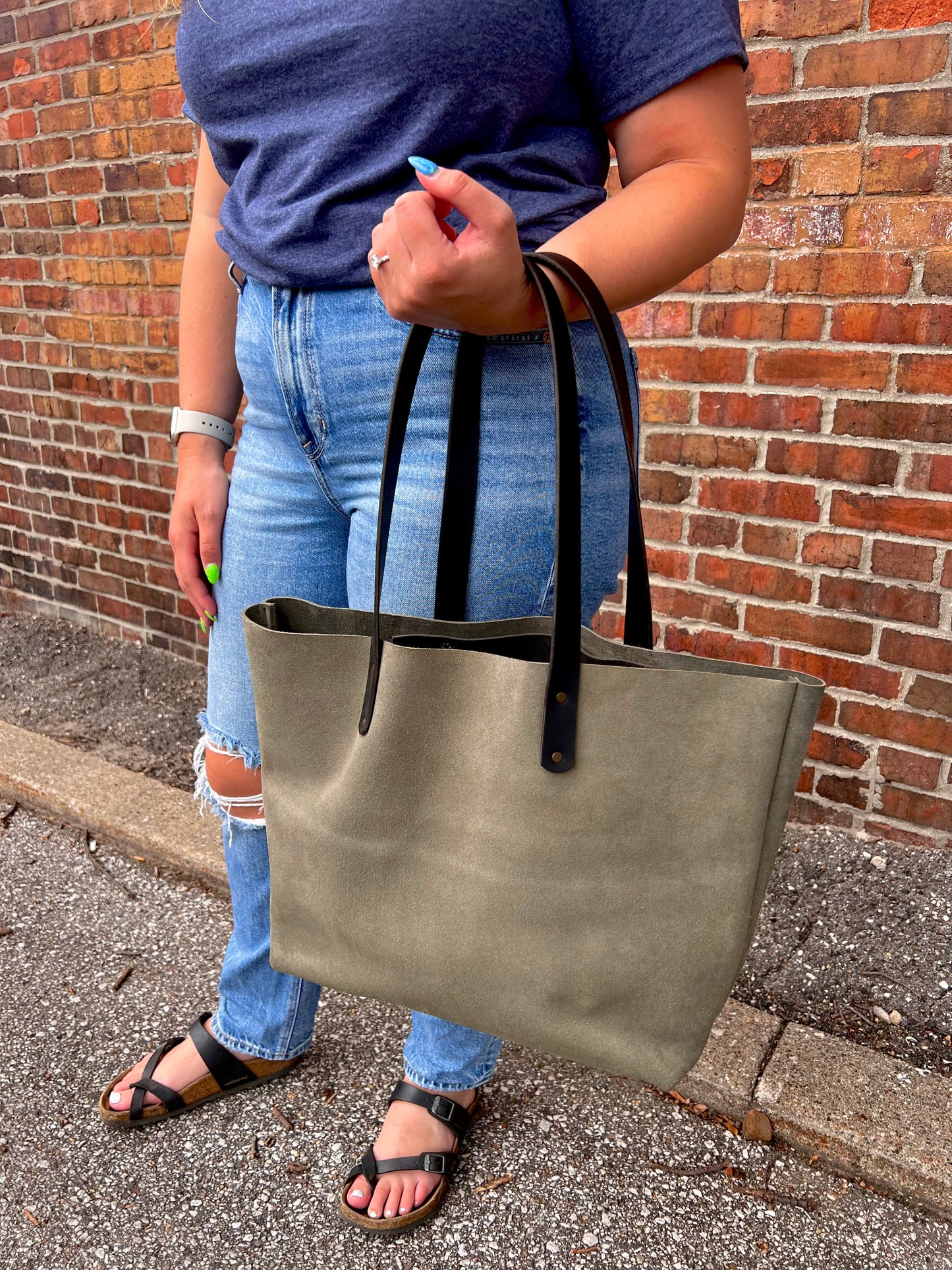 Large moss green suede Wanderer tote bag with black leather straps and brass hardware.
Simple. Rugged. Dependable.
